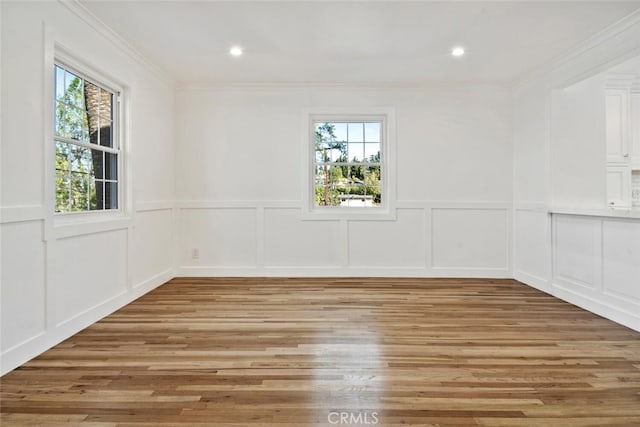 empty room featuring ornamental molding, a wealth of natural light, and light wood finished floors