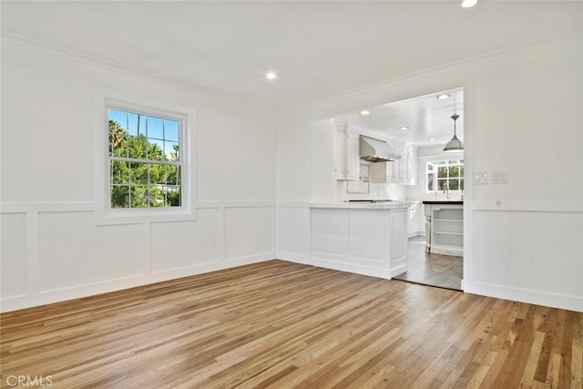 unfurnished living room with light wood-style flooring, crown molding, and recessed lighting