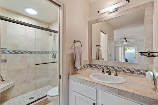 bathroom featuring ceiling fan, vanity, a shower stall, and toilet