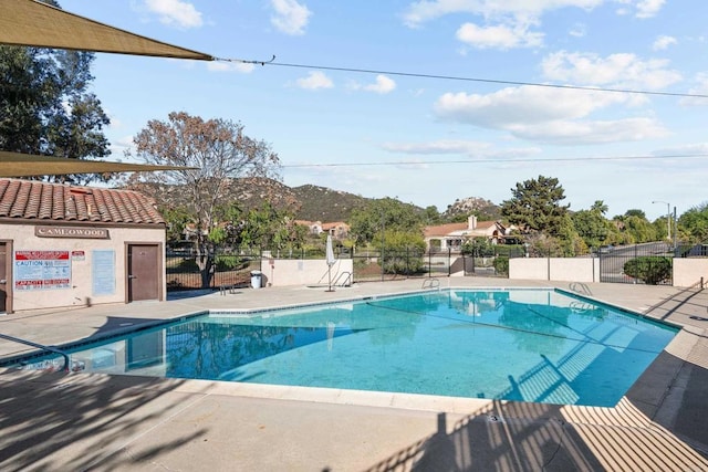 pool with a patio area, fence, and a mountain view