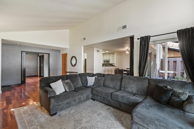 living area featuring dark wood-style floors, visible vents, and high vaulted ceiling