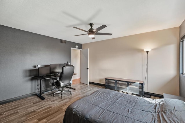 bedroom featuring visible vents, ceiling fan, baseboards, and wood finished floors