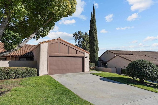 view of front of house featuring a garage, a tiled roof, concrete driveway, and a front yard