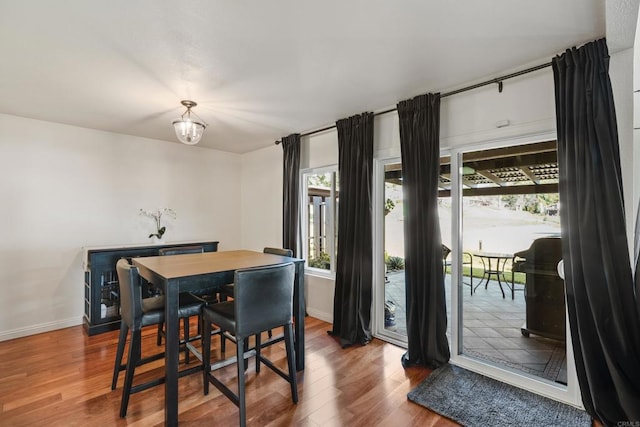 dining space with an inviting chandelier, baseboards, and wood finished floors