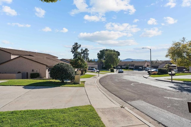 view of street with curbs, street lighting, sidewalks, and a residential view