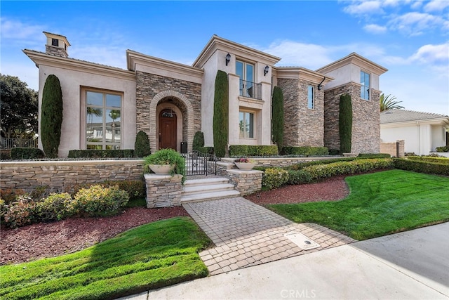 view of front facade featuring stone siding, a balcony, a front lawn, and stucco siding