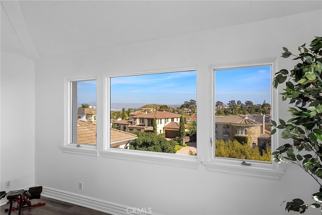 interior space with plenty of natural light, a residential view, baseboards, and wood finished floors