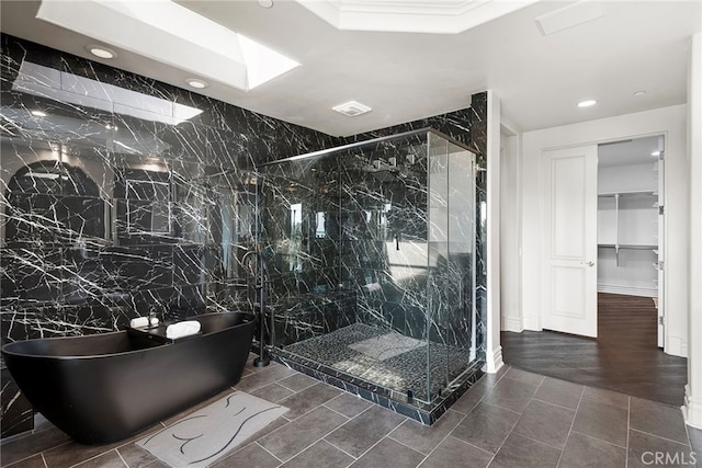 bathroom with a skylight, a marble finish shower, a soaking tub, a spacious closet, and recessed lighting