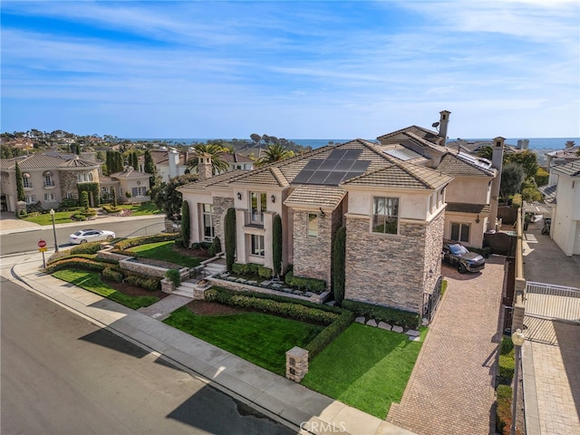 view of front of property with solar panels, a tiled roof, stone siding, a residential view, and stucco siding