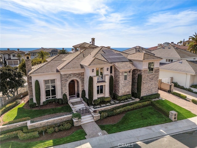 mediterranean / spanish-style home with stone siding, solar panels, a tile roof, and stucco siding