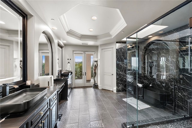 bathroom featuring crown molding, a marble finish shower, double vanity, a raised ceiling, and a sink