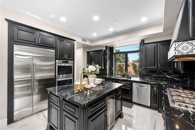 kitchen featuring dark cabinets, premium range hood, visible vents, marble finish floor, and appliances with stainless steel finishes