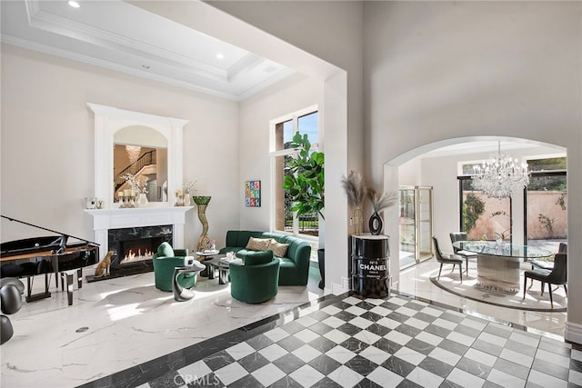 living area featuring a towering ceiling, a fireplace, ornamental molding, and recessed lighting