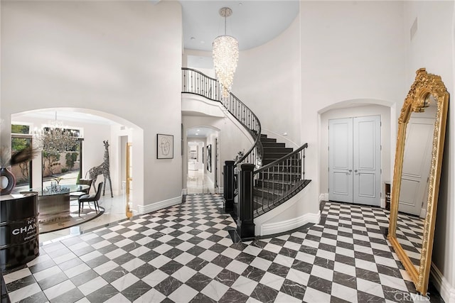 entryway featuring arched walkways, baseboards, stairs, and a notable chandelier