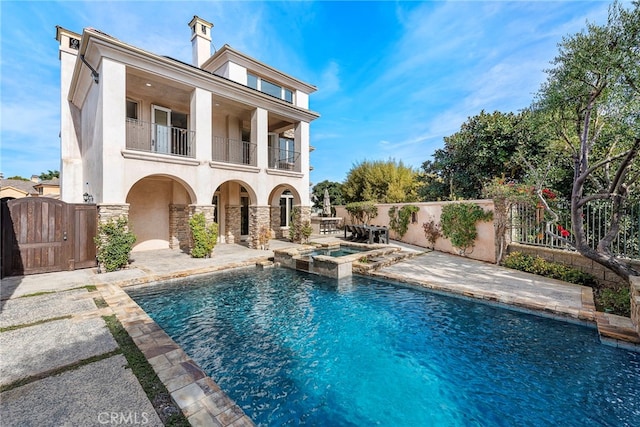 rear view of property featuring fence private yard, a gate, a balcony, and stucco siding