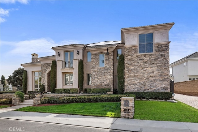 view of front of property with stone siding, a front lawn, fence, and stucco siding