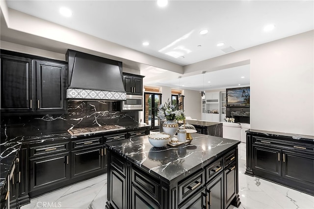 kitchen featuring premium range hood, a kitchen island, open floor plan, appliances with stainless steel finishes, and dark cabinetry