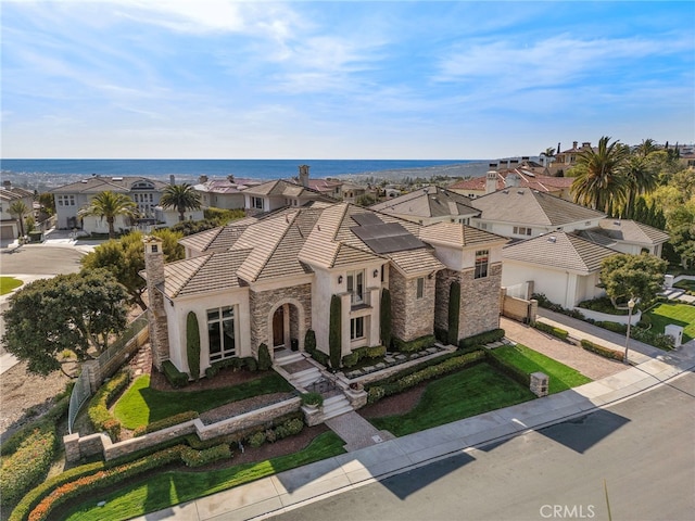 mediterranean / spanish home with stone siding, a residential view, solar panels, and a tiled roof