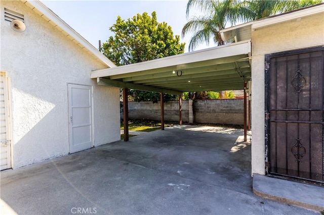 view of parking featuring fence and a carport