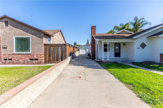 view of property exterior with a yard, a chimney, fence, and stucco siding