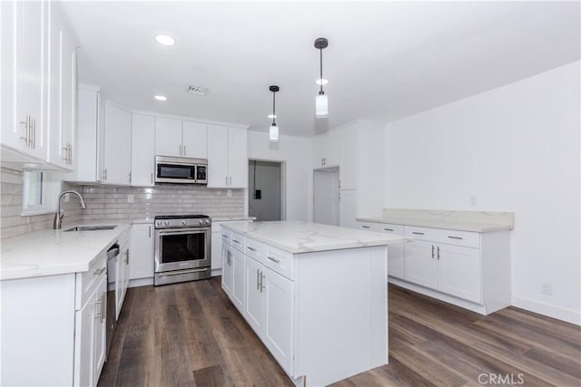 kitchen with white cabinets, stainless steel appliances, a sink, and a center island