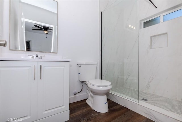 bathroom featuring a marble finish shower, toilet, a ceiling fan, vanity, and wood finished floors