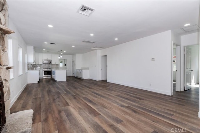 unfurnished living room with a fireplace, visible vents, dark wood-type flooring, and recessed lighting