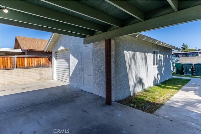 view of property exterior with a patio area, fence, and stucco siding