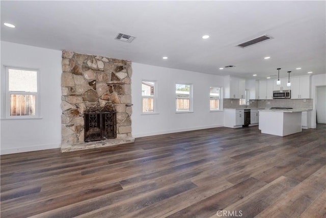 unfurnished living room featuring dark wood-style flooring, visible vents, and a fireplace