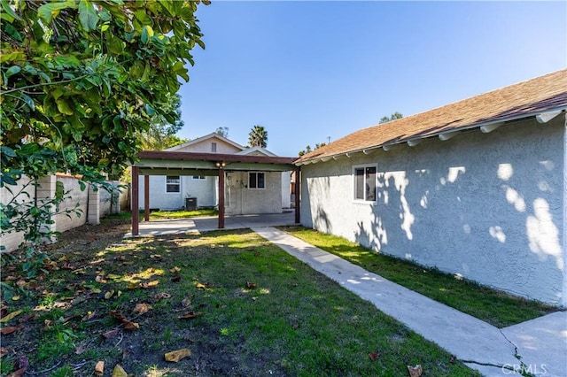 rear view of property featuring a patio area, a fenced backyard, a yard, and stucco siding