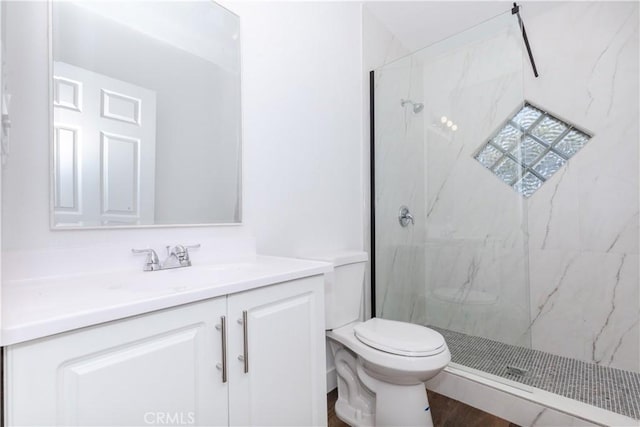 bathroom featuring a marble finish shower, vanity, and toilet