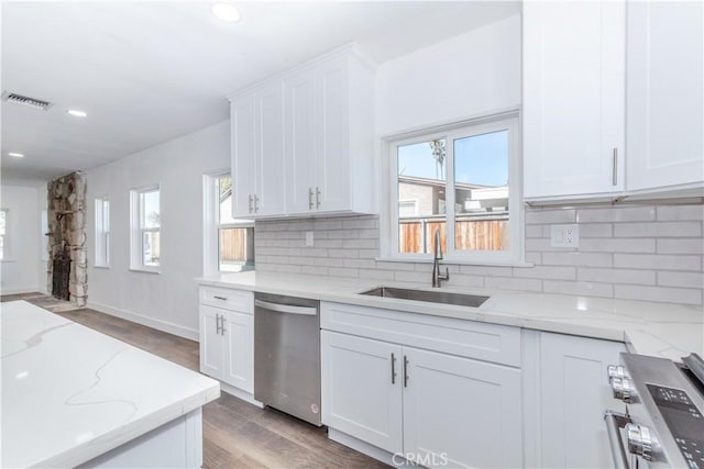 kitchen featuring stainless steel appliances, white cabinets, a sink, and visible vents