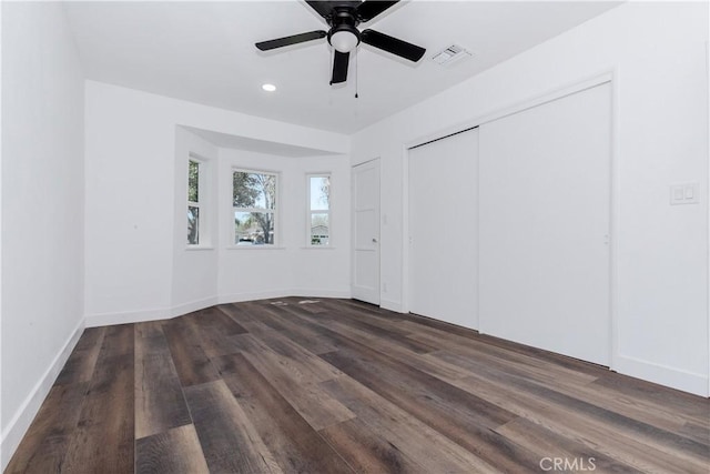 unfurnished bedroom with baseboards, a closet, visible vents, and dark wood-style flooring