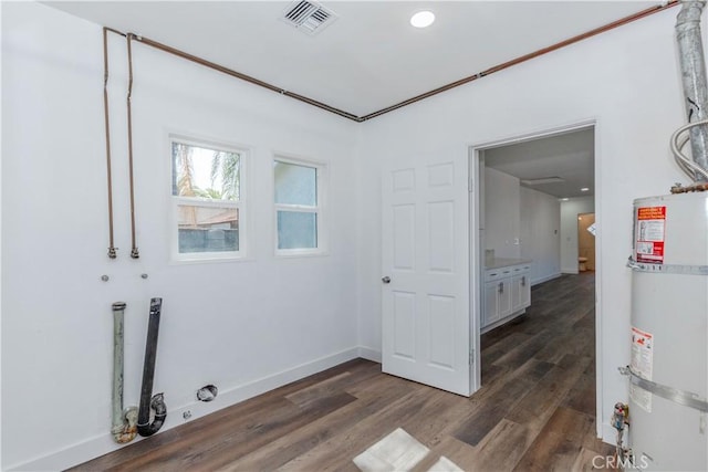 clothes washing area with laundry area, visible vents, baseboards, strapped water heater, and dark wood-type flooring