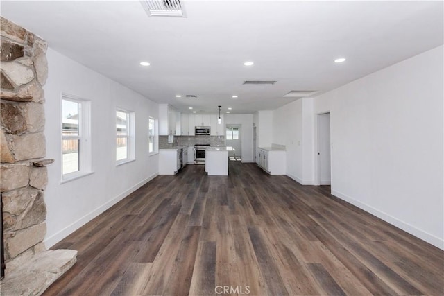 unfurnished living room featuring visible vents, dark wood-type flooring, and a stone fireplace