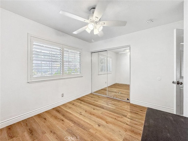 unfurnished bedroom with baseboards, a closet, a ceiling fan, and light wood-style floors