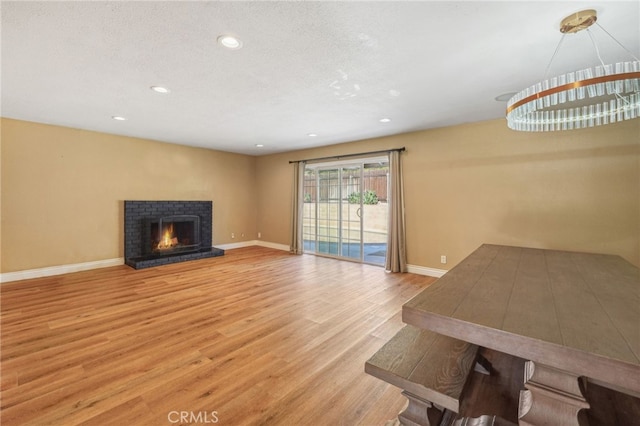 unfurnished living room with a fireplace, recessed lighting, a textured ceiling, wood finished floors, and baseboards