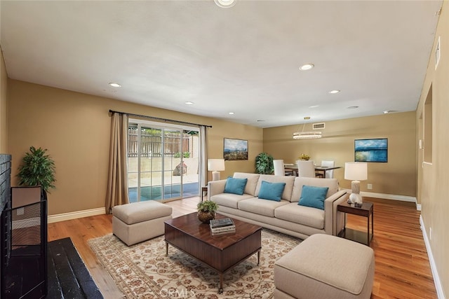 living room featuring recessed lighting, a fireplace, baseboards, and wood finished floors