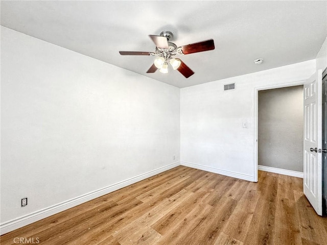 empty room featuring ceiling fan, light wood-style flooring, visible vents, and baseboards