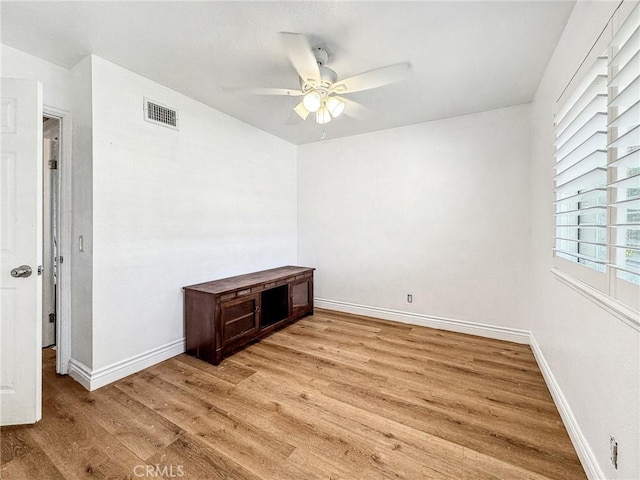 unfurnished room featuring a ceiling fan, light wood-type flooring, visible vents, and baseboards