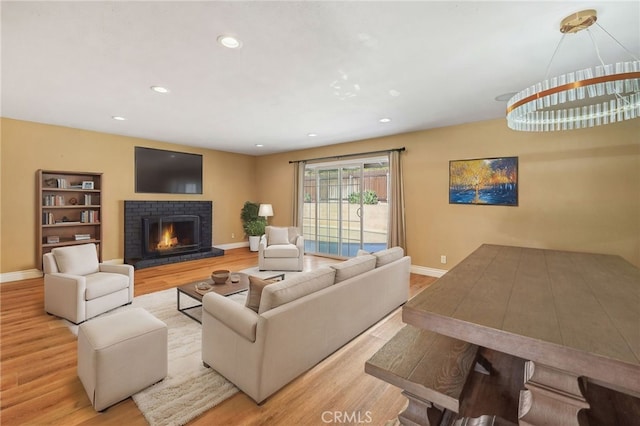 living room with light wood-type flooring, a fireplace, baseboards, and recessed lighting