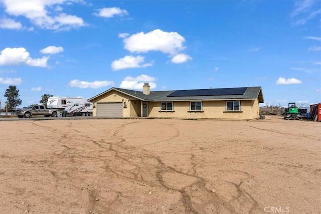 ranch-style house with a garage and roof mounted solar panels