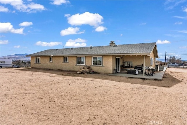 rear view of property featuring a patio area, a mountain view, and stucco siding