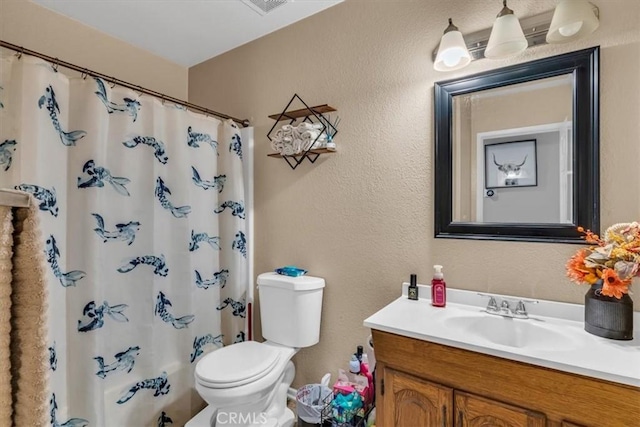 bathroom featuring toilet, curtained shower, a textured wall, and vanity