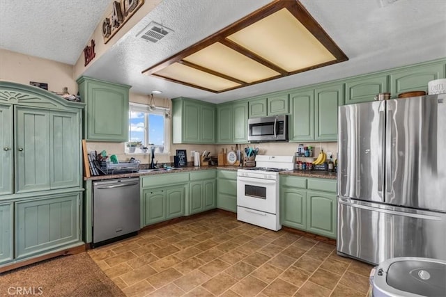 kitchen with stainless steel appliances, dark countertops, visible vents, a sink, and a textured ceiling