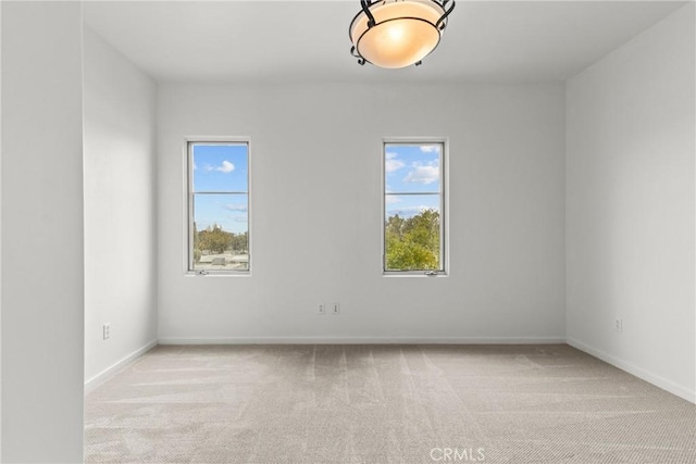 spare room featuring light carpet and baseboards