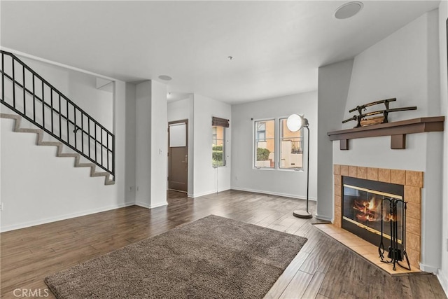 interior space featuring stairway, a tiled fireplace, wood finished floors, and baseboards