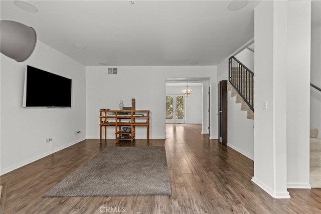 living room featuring baseboards, stairs, visible vents, and wood finished floors