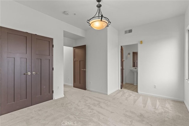 unfurnished bedroom with carpet floors, ensuite bath, visible vents, and baseboards