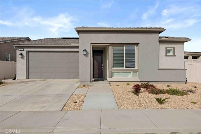 prairie-style home featuring an attached garage, fence, concrete driveway, roof mounted solar panels, and stucco siding